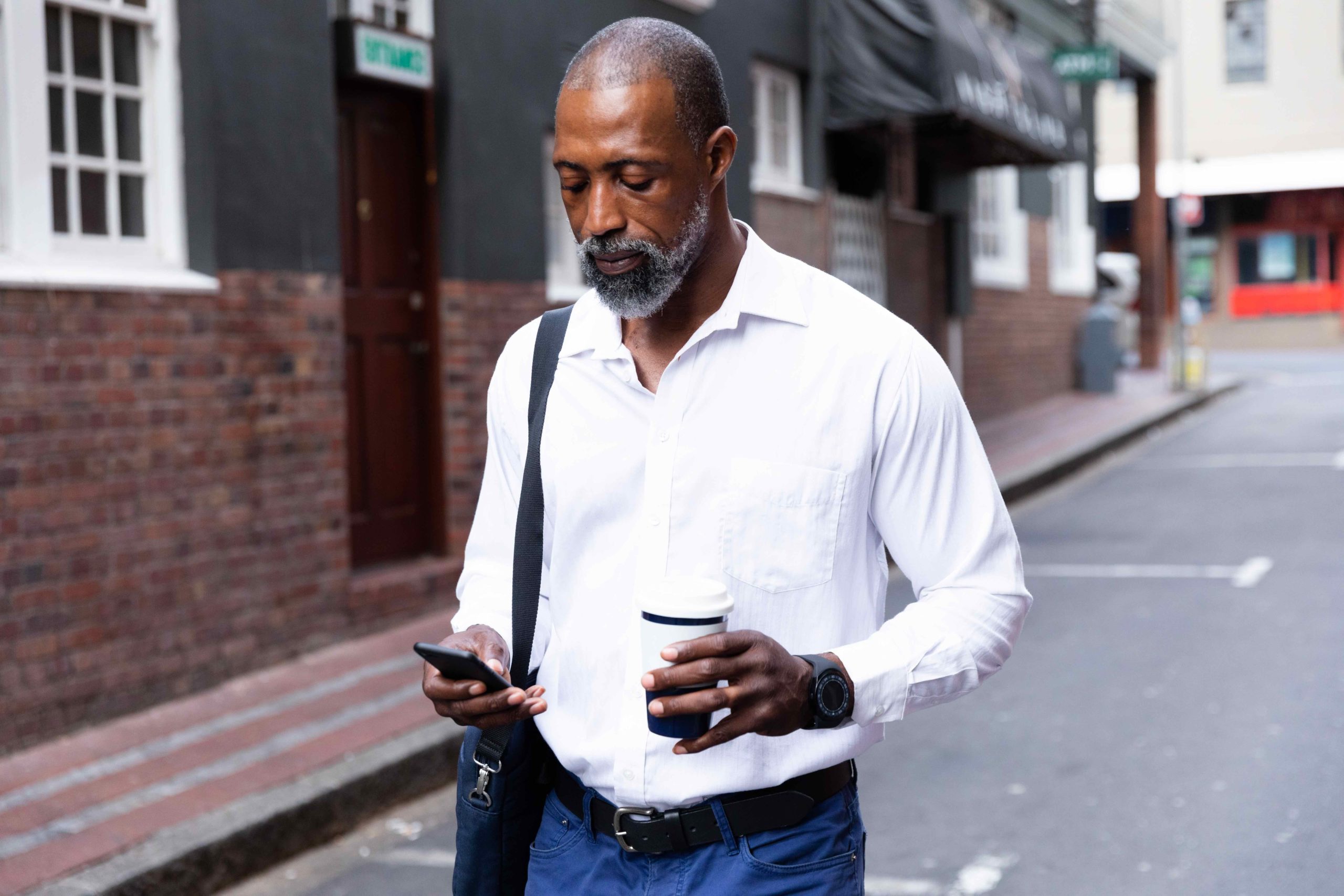 African American man out and about in the city streets during the day, walking down the street, holding a cup of takeaway coffee and using his smartphone. Our unique approach to investing means you can maximize your returns.